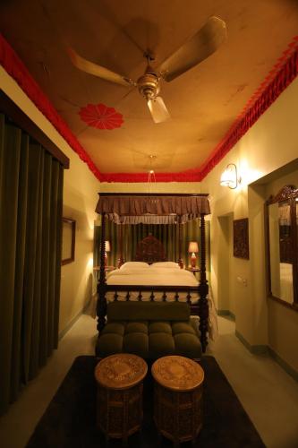 a bedroom with a bed and a ceiling fan at Partap Mahal in Bikaner