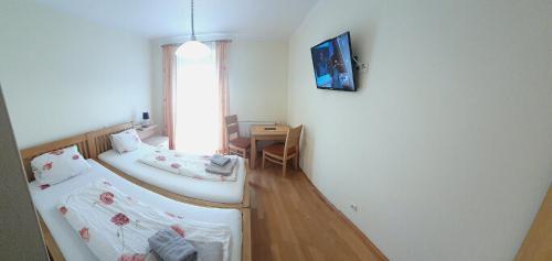 two beds in a room with a table and a window at Gasthof-Pension Ölberger in Wolfsberg