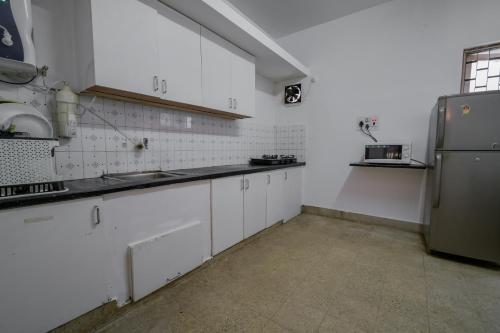 a kitchen with white cabinets and a refrigerator at Snore Summore, Hostel in Koramangala in Bengaluru