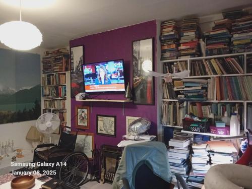 a living room with a purple wall with books at 42 Churchbury vRd, Room 2 in Eltham