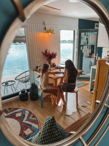 two girls sitting at a table in a room with the water at Costa del Kryspi Całoroczne Domy na Wodzie in Cholerzyn