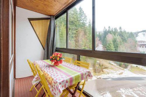 une table et des chaises dans une pièce avec une fenêtre dans l'établissement Belle Hutte - La Bresse montagne et parking privé, à La Bresse