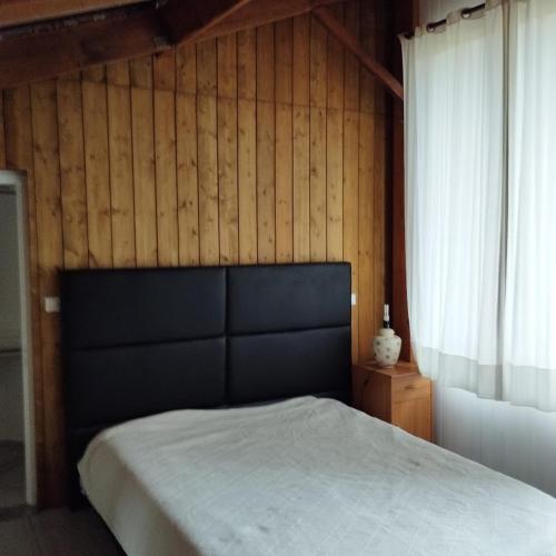 une chambre avec un lit et un mur en bois dans l'établissement Studio 2, à Talais