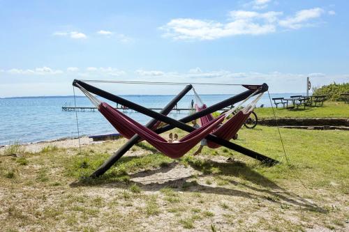 a hammock sitting on the grass next to the ocean at First Camp Bøsøre Strand Feriepark in Hesselager
