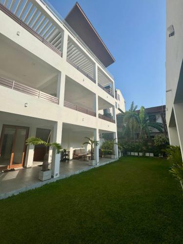 a large white building with a lawn in front of it at Aurora Holiday House in Mount Lavinia