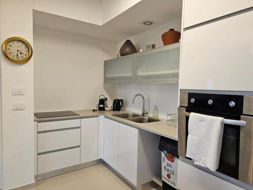 a kitchen with white cabinets and a clock on the wall at Savyon View Royal Suites - Alefimmoed in Jerusalem