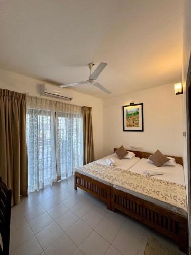 a bedroom with a large bed and a ceiling fan at Aurora Holiday House in Mount Lavinia