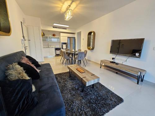 a living room with a black couch and a table at Savyon View Royal Suites - Alefimmoed in Jerusalem