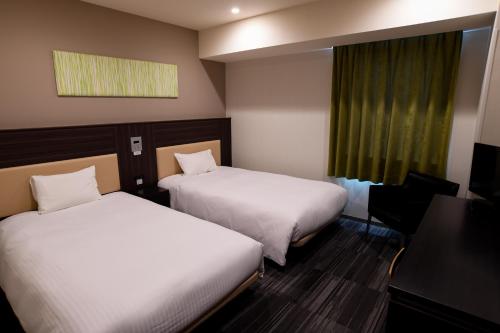 a hotel room with two beds and a window at Washington R&B Hotel Hachioji in Hachioji