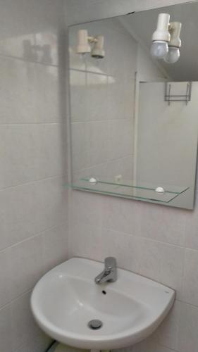 une salle de bain blanche avec un lavabo et un miroir dans l'établissement Très Centrale studio mais aux calme!, à Nice