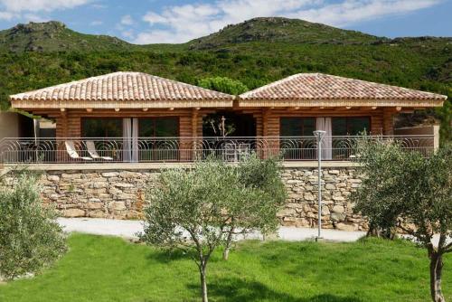 une maison avec un mur en pierre et des montagnes en arrière-plan dans l'établissement Domaine La Pietra, à Pietracorbara