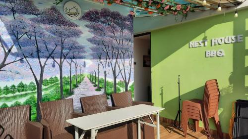 a wall with a mural of trees and a table and chairs at NEST House in Ấp Kim Thạch