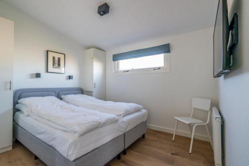 a small bedroom with a bed and a chair at Buitenplaats Oudendijke in Ellemeet