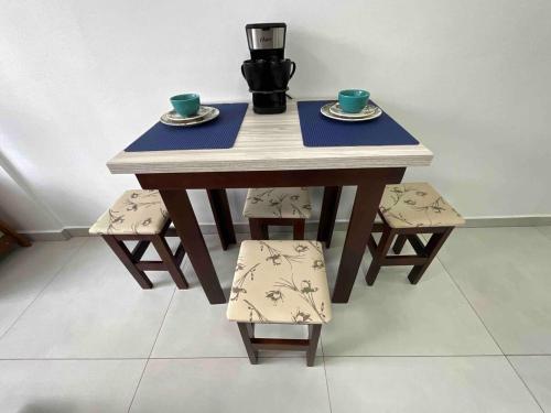 a wooden table with two cups and two chairs at Studio Balneário Camboriú SC Com Vista Para o Cristo Luz Perto da Praia in Balneário Camboriú