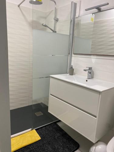 une salle de bain blanche avec un lavabo et une douche dans l'établissement Catalunya Les 3 gîtes jardin vue montagne calme T2, à Dorres