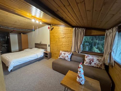 a bedroom with a bed and a couch in a room at Villa Raiski kyt in Dospat