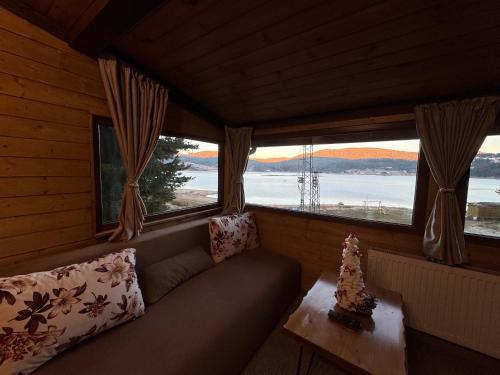 a room with a couch and a table and windows at Villa Raiski kyt in Dospat