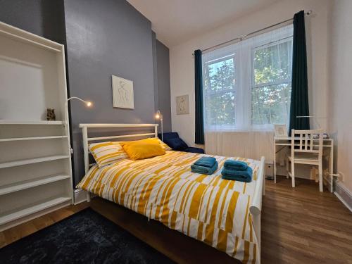 a bedroom with a bed with yellow sheets and a window at Modern Spacious Rooms 10 Minutes from Big Ben in London