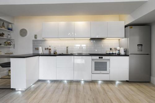 a white kitchen with white cabinets and a wooden floor at Manor House Apartment - Indoor Heated Pool, Parking in Torquay