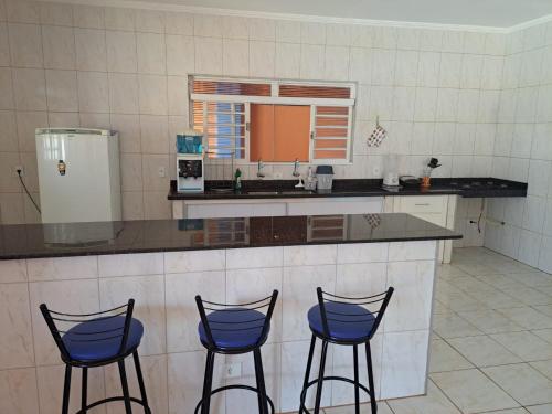una cucina con tre sgabelli da bar blu e un bancone di Espaço Portal Azul a Casa Branca