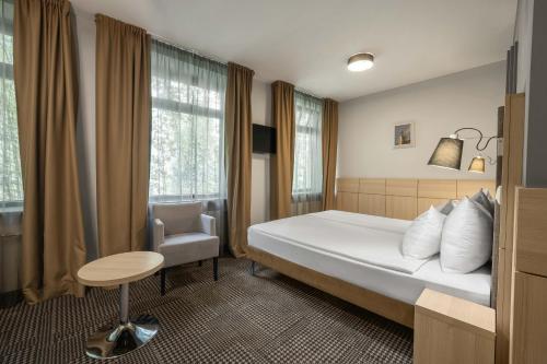 a hotel room with a bed and a chair at Wellton Centrum Hotel & SPA in Rīga