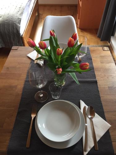 a table with a white plate and a vase of flowers at mama käthe - Apartments in Nenzing