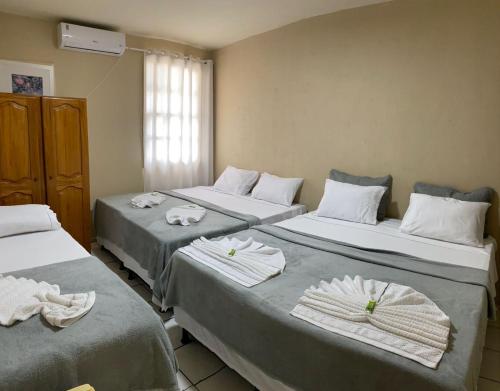 three beds in a room with towels on them at Pousada da Orla in Itacaré