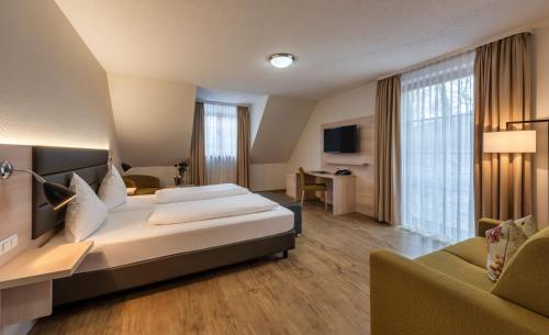 a hotel room with a large bed and a couch at Hotel-Restaurant Bibermühle GmbH in Tengen