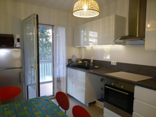 une cuisine avec un évier et un comptoir avec des chaises rouges dans l'établissement BANDOL 