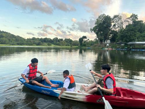 three men are sitting in a kayak on a lake at Camping Phuket 88 in Kathu