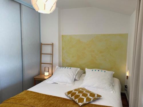 une chambre avec un lit avec un oreiller dessus dans l'établissement Okaido Les 3 gîtes vue montagne jardin ancien T3, à Dorres