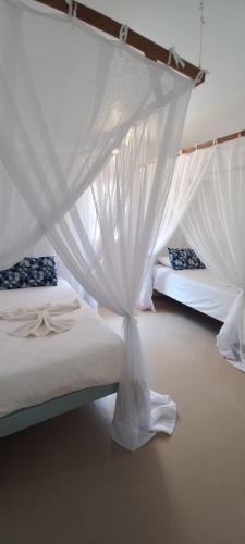 a bedroom with two beds with white mosquito nets at Baobab Beach Vilanculos in Vilanculos