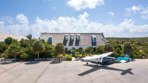 a small plane parked in front of a building at Ambergris Cay - Private Island All-Inclusive in Big Ambergris Cay