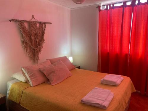 a bedroom with red curtains and a bed with two towels at DepartamentoSantaInes in Viña del Mar