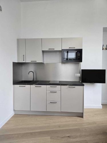 une cuisine avec des armoires blanches et un micro-ondes dans l'établissement Studio Grands Boulevards, à Paris