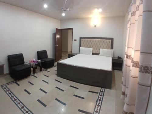 a bedroom with a bed and two chairs in it at Subhan Inn in Karachi