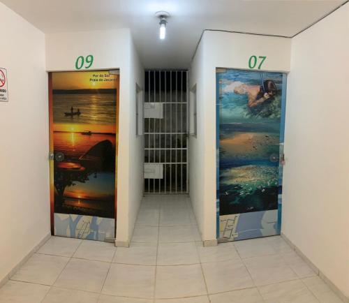 a hallway with two doors with paintings on them at Pousada e Hostel Camboinha in Cabedelo