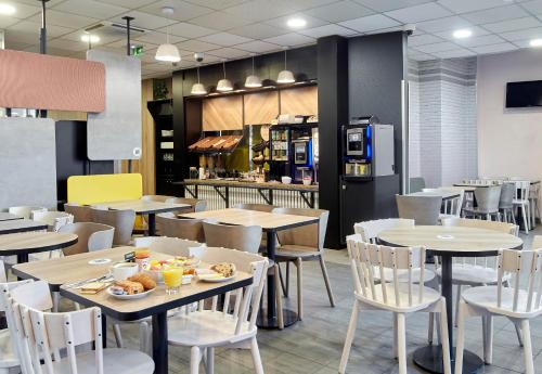 a restaurant with tables and chairs and a kitchen at B&B HOTEL Paris Saint-Denis Pleyel in Saint-Denis