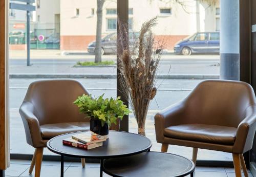two chairs and a table with a vase of flowers at B&B HOTEL Paris Saint-Denis Pleyel in Saint-Denis