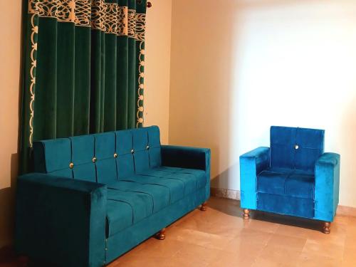 a blue couch and two blue chairs in a room at Subhan Inn in Karachi