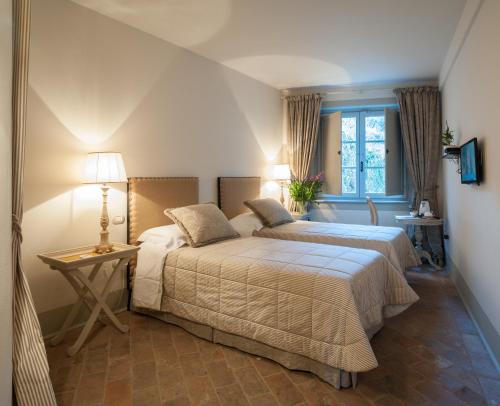 a bedroom with two beds and a table and two lamps at B&B Pieve Degli Artisti in Pietrasanta