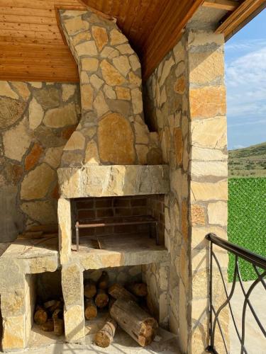 an outdoor stone fireplace with a wooden roof at Camp Hotel Pura Vida in Tbilisi City