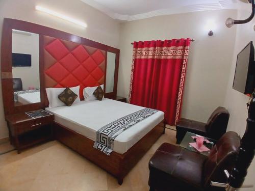 a bedroom with a large bed and a red curtain at Subhan Inn in Karachi