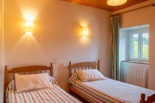 two beds in a room with two lights on the wall at Gîte Gîtes de France 6/7 personnes 3 chambres in Chaulhac