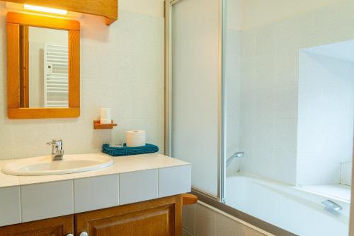 a bathroom with a sink and a mirror and a tub at Gîte Gîtes de France 6/7 personnes 3 chambres in Chaulhac