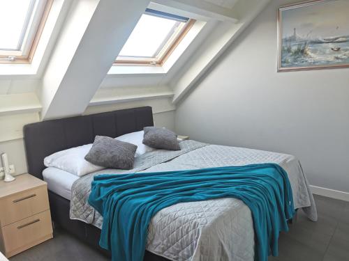 ein Schlafzimmer mit einem Bett mit einer blauen Decke darauf in der Unterkunft Apartamenty Wybrzeże Laguna II in Ustronie Morskie
