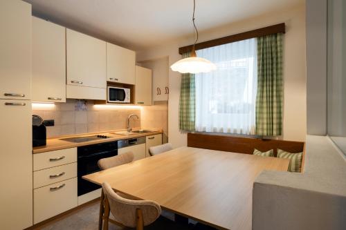 a kitchen with a wooden table with chairs and a window at AppartChalet LA RONDULA - 100m from Seceda in Ortisei