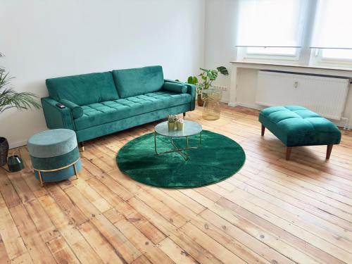 a living room with a green couch and a table at Möbliert-nahe STARLIGHT EXPRESS in Bochum -WLAN-Netflix-Loggia oder Terrasse in Bochum
