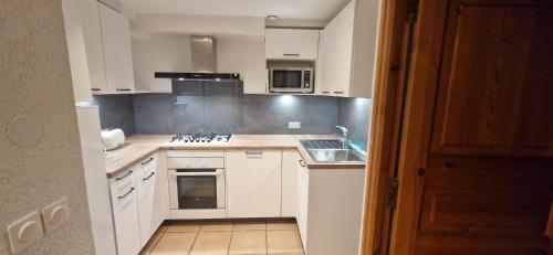 a kitchen with white cabinets and a stove top oven at Appartement 11 personnes in Saint-Martin-de-Belleville