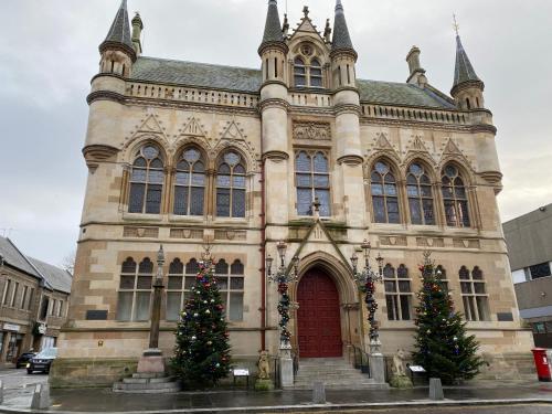 an old building with christmas trees in front of it at No 10 Immaculate City Centre, Top Floor 2 Bed Flat with Free Parking in Inverness